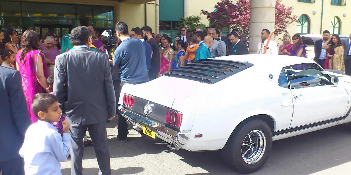 A wedding car decorated for an Asian wedding, parked outside a temple.