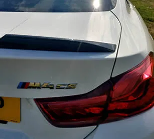 Rear view of the BMW M4 with Alpine white paintwork and carbon detail.